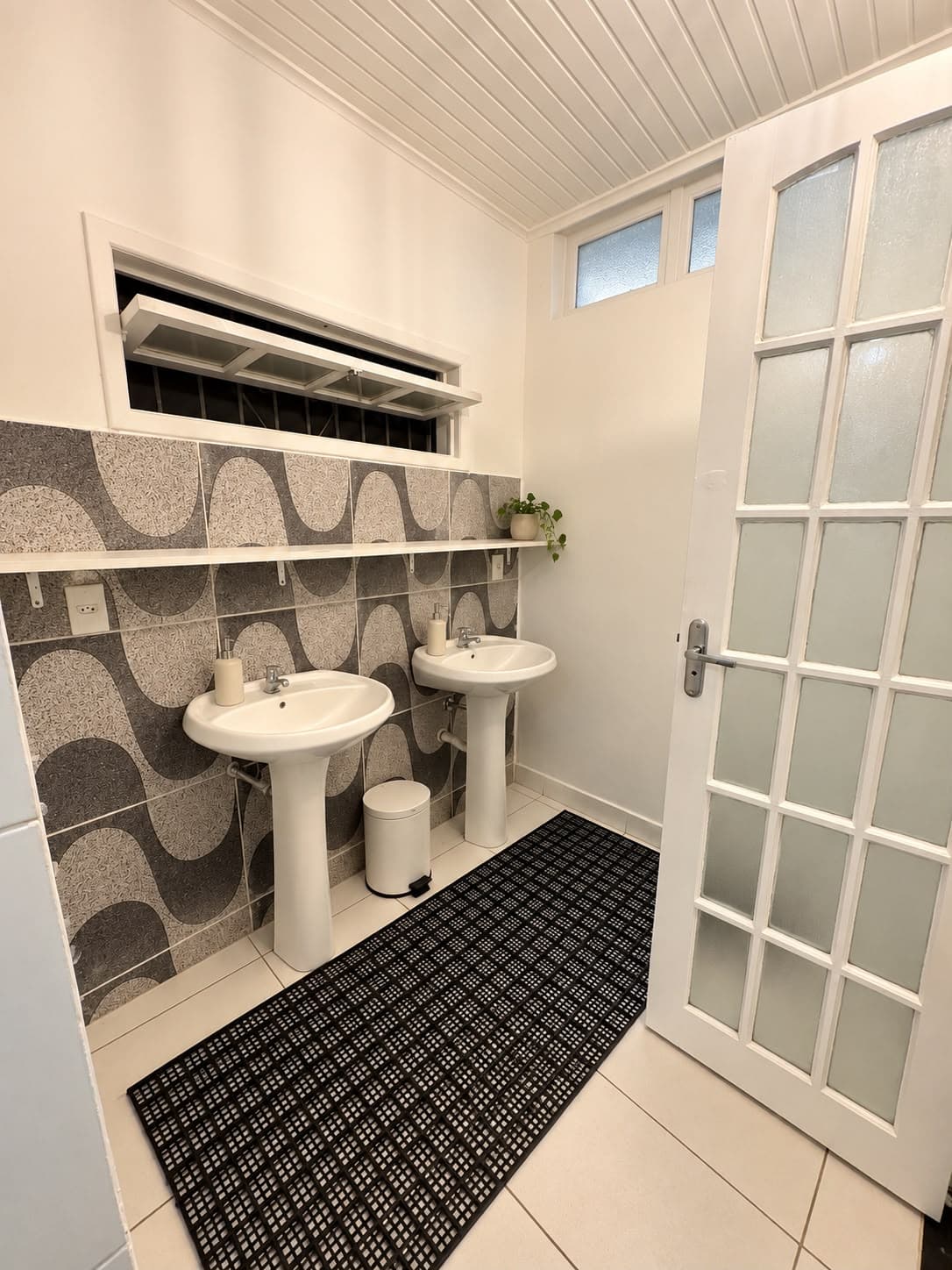 Pias com azulejos de ondas pretas e brancas e porta de vidro
