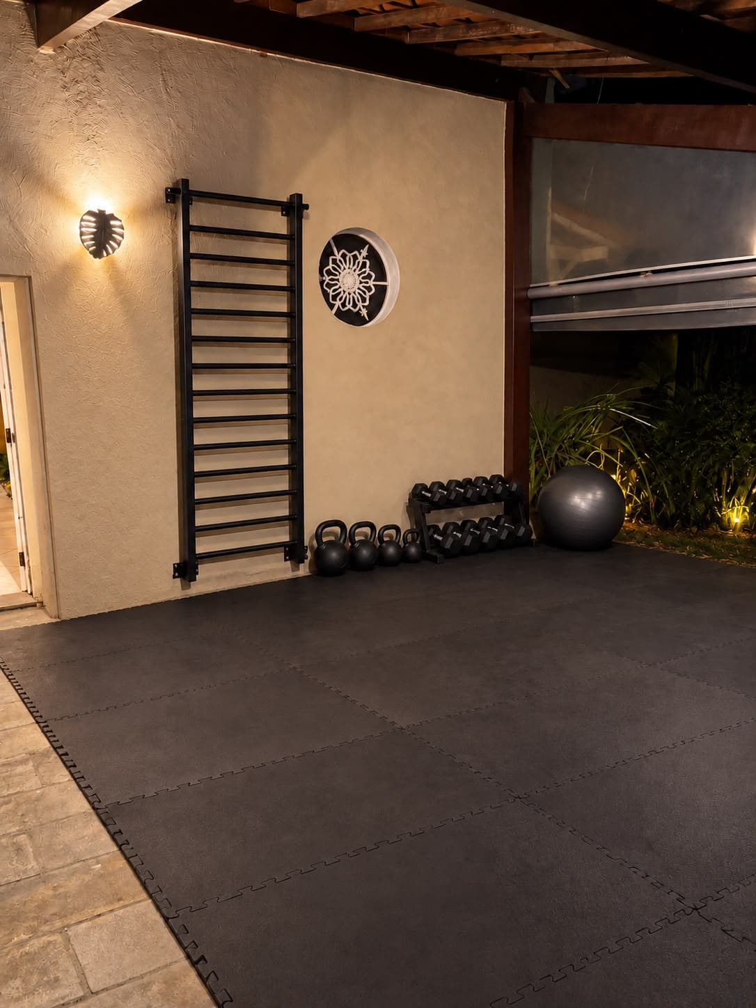 Área de treino com tatame, espaldar, kettlebells e halteres